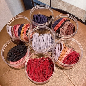 Top view of colorful elastic hair bands stored in transparent jars on a brown surface
