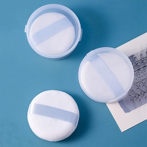 Three white round loose powder puffs with blue ribbons and a clear storage case
