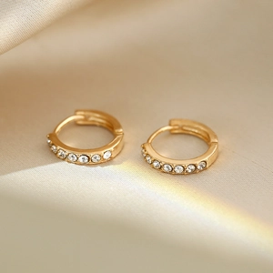 Macro shot of gold hoop earrings with sparkling white zircons on a silk background