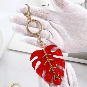 Detail of red monstera leaf keychain with gold glitter acrylic and metallic veins