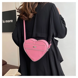 Detail of pink heart-shaped crossbody bag with silver hardware and double zippers