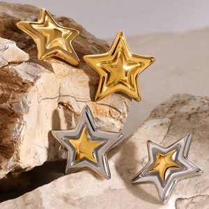 Polished star stud earrings in gold and silver finish set on a natural rock surface