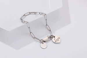 Macro shot of silver chain bracelet with heart Love charm and circular pendant
