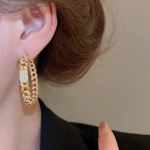 Detailed close-up of 18k gold-plated curb chain earrings with sparkling cubic zirconia pavé