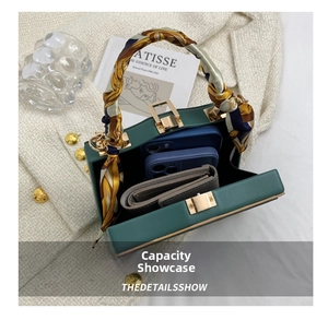 Detail of dark green leather box bag interior showing capacity for phones and wallet