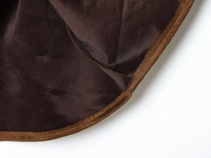 Gros plan sur tissu marron foncé avec passepoil en daim beige et coutures précises