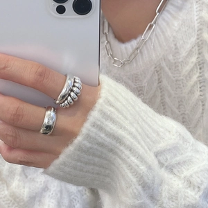 Detail of 925 sterling silver knotted ring and paperclip necklace in minimalist style