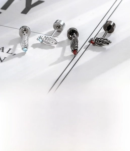Detail view of angel wing cartilage piercings with inlaid zircon and steel flat backs