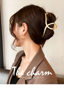 Close-up of elegant gold metal hair claw and twisted hoop earrings on a fashion model