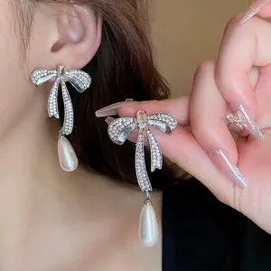 Elegant silver bow zircon earrings with drop pearls shown in a lifestyle model shot