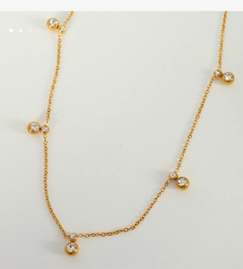 Macro shot of gold-plated choker necklace with round-cut zircon stones on a gray background