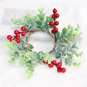 Macro view of Christmas candle ring with frosted green leaves and red berries