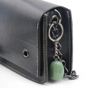 Detail of natural green agate stone pendant hanging from a black leather shoulder bag chain
