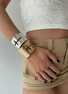 Detail of wide textured metal cuff bracelet with hollow cross design in gold finish