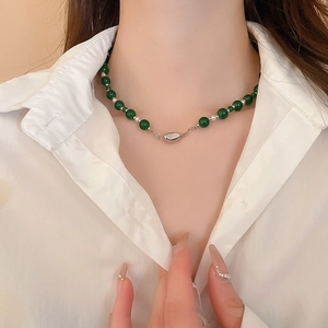 Détail macro du collier de perles en verre vert émeraude avec fermoir magnétique argenté