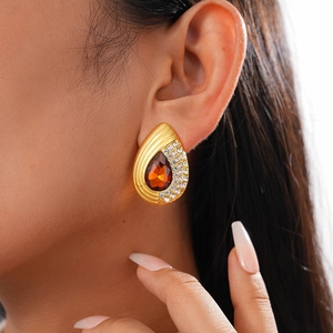 Detail of amber waterdrop earring with crystal accents on a model's ear lobe