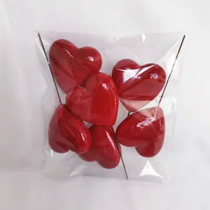 Close-up of red heart cake toppers with glossy finish and metal sticks in pack
