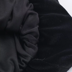 Makroaufnahme von schwarzem Samtstoff mit dekorativer Schleife und Strickmaterial-Details