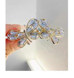 Close-up of golden metal bow hair clip with sparkling silver zircon rhinestones