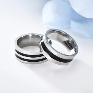 Close-up of minimalist titanium steel couple rings with black enamel stripe detail