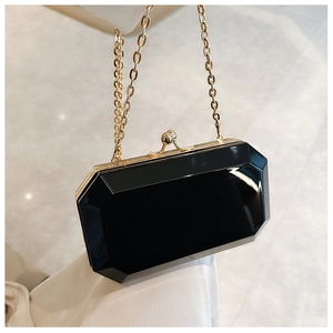 Macro view of geometric acrylic evening clutch with gold metal frame and chain strap