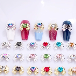 Bowknot nail art charms with heart-shaped zircon displayed on various manicured nails