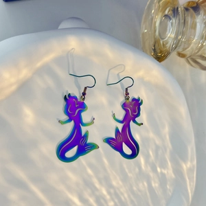 Detail of colorful iridescent mermaid dangle earrings on a textured water-shadow background