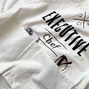 Detail view of cotton linen apron front pocket holding a smartphone and glasses