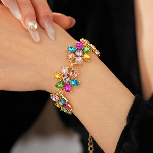Detailed view of a vintage gold floral bracelet with multi-colored crystals on a wrist
