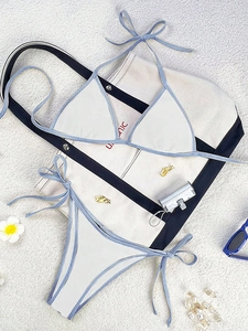 Flat lay of white bikini set with blue trim, beach bag and vacation accessories