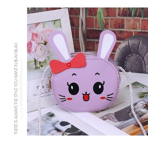 Detail of purple cartoon kids crossbody bag with bunny ears and bow on red brick wall