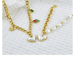 Close-up of golden necklace and pearl bracelet with heart and butterfly charms