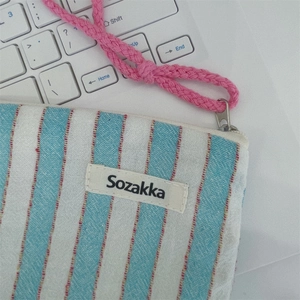 Detail of blue striped canvas bag with Sozakka label and pink woven strap handle