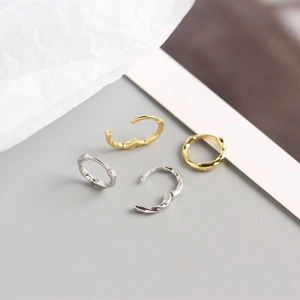 Detailed close-up of small twisted rope earrings in polished gold and silver finishes