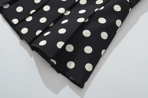 Détails de la jupe plissée noire à pois blancs montrant la texture du tissu gaufré