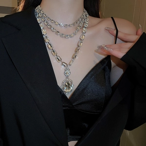 Detail of multi-layer silver necklace with square crystals and pear-shaped drop pendant