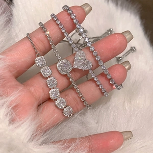 Gros plan de bracelets en argent avec zircons en cœur et carrés sur fourrure blanche
