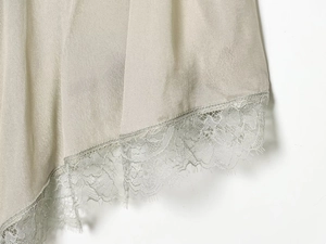 Macro detail of champagne silk dress hem featuring delicate lace trim and smooth fabric