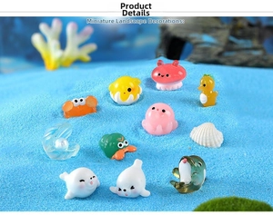 Miniature ocean animal figurines including crab and octopus on light blue sand background