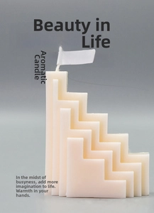 Close-up of geometric S-shaped tiered scented candle in creamy white with paper tag