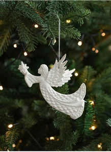 Detail of white glittery angel wing ornament hanging on a Christmas tree with warm lights