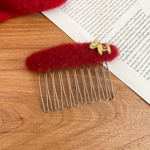 Detailed macro view of a red plush hair comb with a golden pony metal ornament