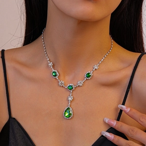 Détail d'un collier en Y argenté avec zircon vert en forme de goutte d'eau sur mannequin