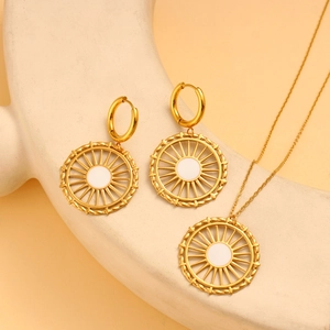 Vue macro de parure collier et boucles d'oreilles dorés en acier et émail blanc