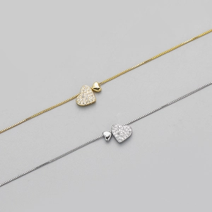 Close-up of gold and silver heart necklaces with small diamonds and box chain details