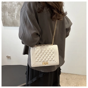 Detail of white quilted leather bag with gold chain strap and metallic lock clasp