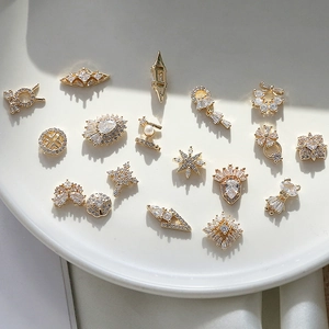 Dettaglio di ciondoli per nail art geometrici dorati con zirconi e perle micro-pave