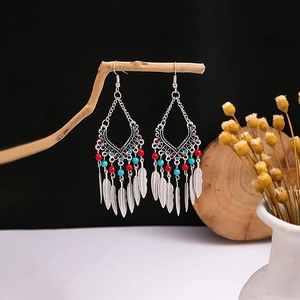Detail of bohemian ethnic earrings with turquoise beads and silver feather tassels