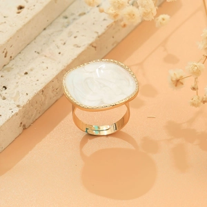 Detail of golden adjustable ring with white enamel square face and beaded edge decor