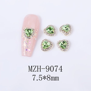 Macro shot of 7.5x8mm grass green heart-shaped nail gems with silver crystal borders